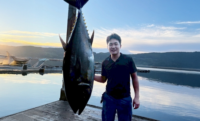水揚げした、全長が身長と同じぐらいの巨大なマグロと一緒に写るF.T.さん