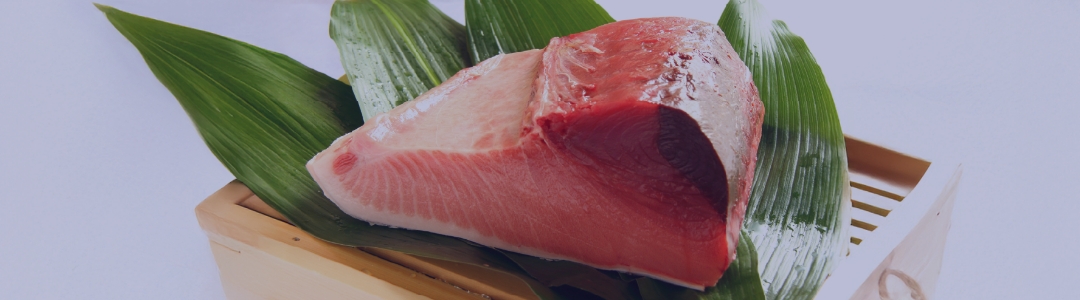 大きなマグロのブロックが、木製のネタ箱の上に置かれている